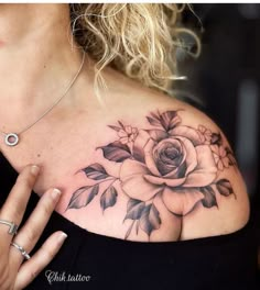 a woman's chest with a rose tattoo on her left shoulder and the other arm