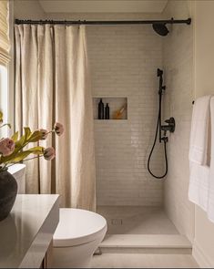 a bathroom with a shower, toilet and sink in it's center area next to a window