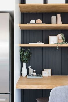 a kitchen with black painted walls and wooden shelves on the wall, along with an office chair