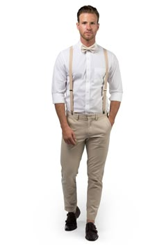 a man wearing suspenders and a white shirt is standing with his hands in his pockets