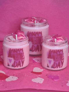 three candles are sitting on a pink tablecloth with hearts and the words happy mother's day