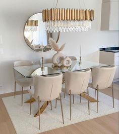 a dining room table with white chairs and a chandelier hanging from the ceiling