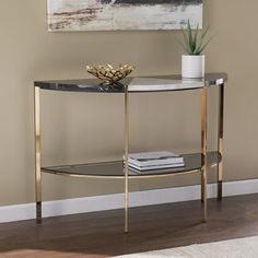 a glass and metal console table in a living room with a painting on the wall