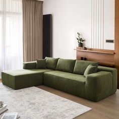 a living room with a large green couch and white rug in front of the window