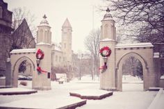 two stone archways with wreaths on them in the middle of a snow covered park