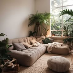 a living room filled with lots of furniture next to a large window and potted plants