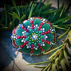 a painted rock sitting on top of a wooden table next to green leaves and grass