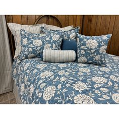 a bed covered in blue and white floral comforter with two pillows on top of it