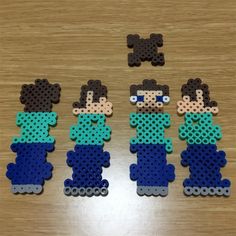 four pieces of perler bead are arranged on a table, including one man and two women