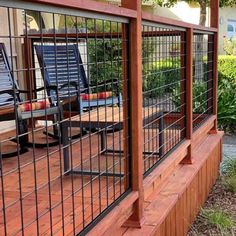 a wooden deck with two chairs on it and a metal fence around the top rail