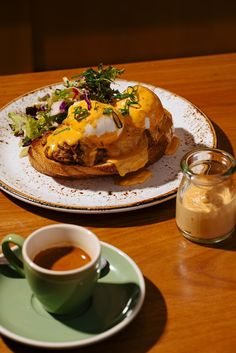 a plate with a sandwich on it next to a cup of coffee