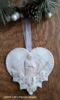 a heart shaped ornament hanging on a table with pine cones and evergreen branches