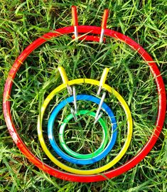 four colored hoses sitting in the grass on top of each other with two handles