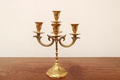 a gold candelabra with five candles on it sitting on a wooden table