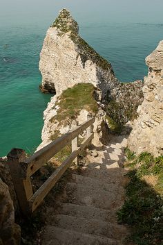 stairs lead down to the beach and into the water at high tide, with cliffs in the background