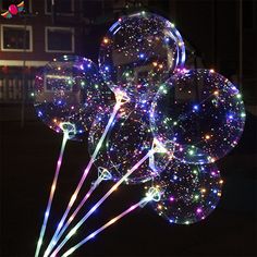 several clear balloons are lit up in the dark with colorful lights on them and sparkles all around