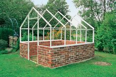 a brick wall with a greenhouse built into it in the middle of some grass and trees