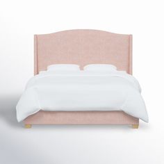 a bed with a pink headboard and white linens on the bottom, in front of a light colored wall