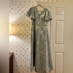 a dress hanging on a wall next to a door with a lamp in the corner