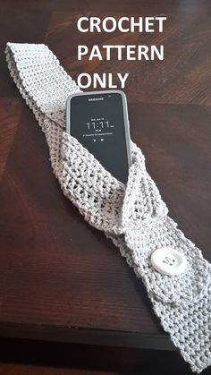 a white crochet tie sitting on top of a table next to a cell phone