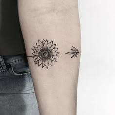 a black and white photo of a sunflower tattoo on the left arm, with an arrow in the middle