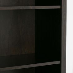 an open bookcase with black shelves and white walls