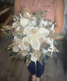 a bridal bouquet with white flowers and greenery is held by a woman's legs