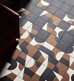 a tiled floor with black and white designs on it's sides, next to a chair