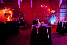 a room with tables and chairs covered in black cloths, decorated with halloween decorations