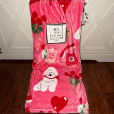 a pink towel with poodles and hearts on it sitting on a wooden floor