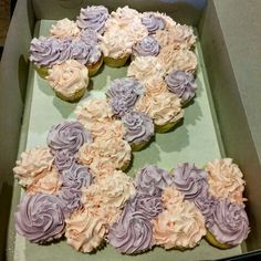 cupcakes in a box decorated with purple and white frosting flowers are ready to be eaten