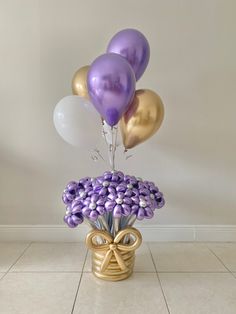 a vase filled with purple and white balloons on top of a tiled floor next to a wall