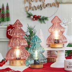 three glass christmas trees sitting on top of a table