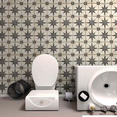 a white toilet sitting next to a sink under a bathroom faucet in front of a tiled wall