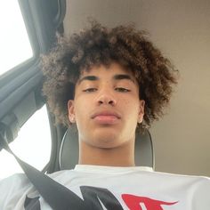 a young man with curly hair sitting in a car