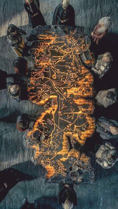 a group of people sitting around a table covered in fire and skulls on the ground