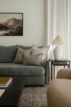 a living room filled with furniture and a painting on the wall above it's windows