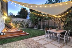 an outdoor patio with string lights strung over the table and steps leading up to it