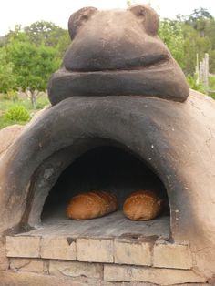 two croissants are sitting in front of an outdoor oven that looks like a frog