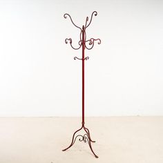 a red metal coat rack with two hooks on it's sides and an umbrella holder attached to the top