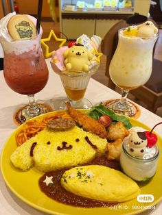 a yellow plate topped with different types of food next to two glasses filled with drinks