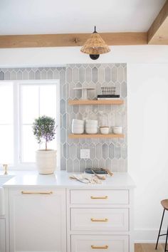 a kitchen with white cabinets and gold pulls on the doors, open shelving shelves