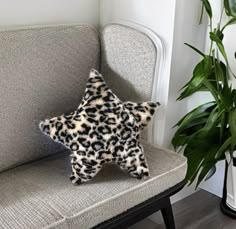 a leopard print star pillow sitting on top of a couch next to a potted plant