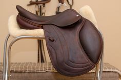 a brown horse saddle sitting on top of a metal chair next to a white rug