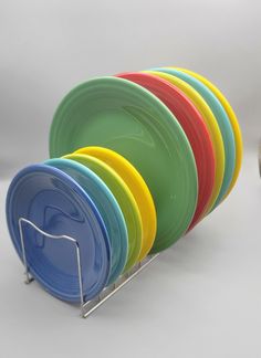 a stack of colorful plates sitting next to each other on a white table with a metal rack