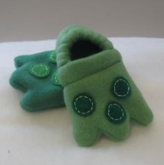 two green slippers sitting on top of a white sheet