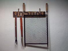 there is a metal rack with tools hanging on the wall next to two forks and a spatula