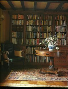 a room filled with lots of books on top of a wooden table next to a chair