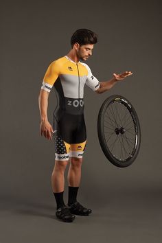 a man holding a bicycle wheel while standing next to a black and yellow bike tire