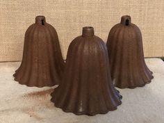 three brown bell shaped vases sitting on top of a table